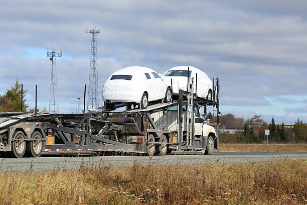 Semi truck car carrier on a highway carrying cars . Cars are covered for protection.
